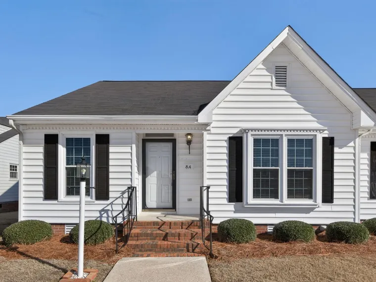 Single-story white siding townhome with black shutters, brick front steps and trimmed shrubs at 2400-8A Bradford Dr N, Wilson, NC 27896